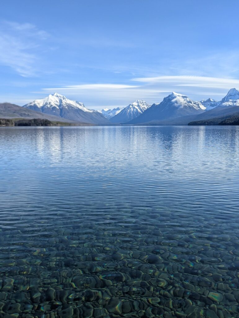 Lake McDonald in Glacier national Park. It's a clear day and there are mountains in the background.